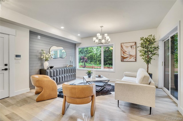 living area featuring baseboards, recessed lighting, light wood-type flooring, and an inviting chandelier