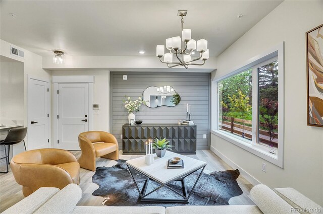 living room featuring baseboards, visible vents, a notable chandelier, and light wood finished floors