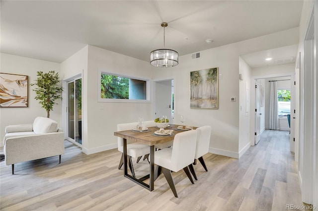 dining area with a chandelier, baseboards, and light wood finished floors