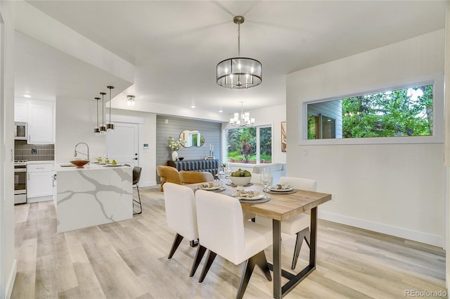 dining room with light wood-style floors, a notable chandelier, and baseboards