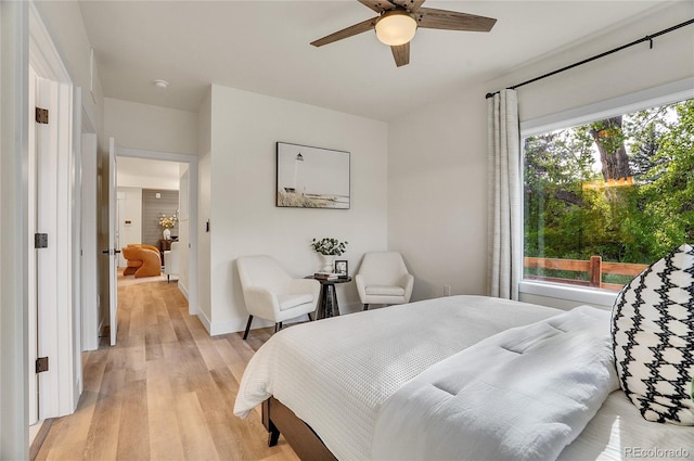 bedroom featuring light wood-style floors, multiple windows, baseboards, and a ceiling fan