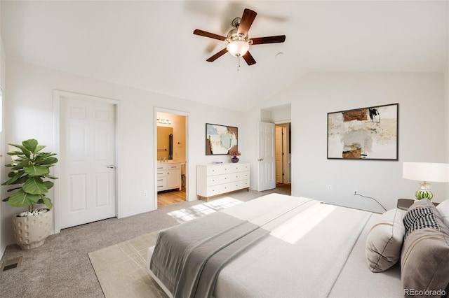 carpeted bedroom with ensuite bathroom, ceiling fan, and vaulted ceiling