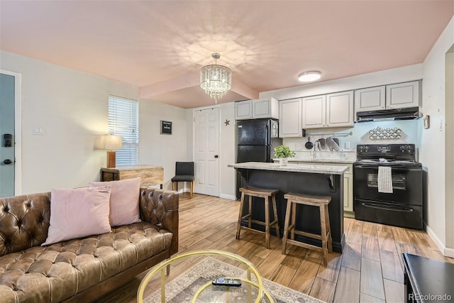 kitchen featuring light stone counters, decorative light fixtures, gray cabinets, and black appliances