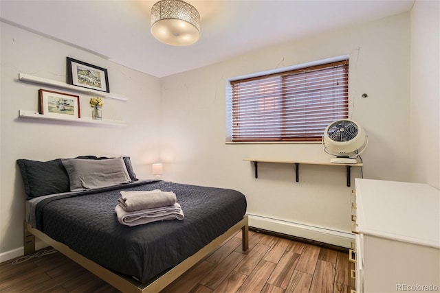 bedroom with wood-type flooring and a baseboard heating unit