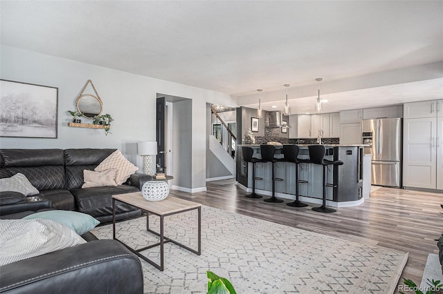 living area featuring baseboards, wood finished floors, and stairs