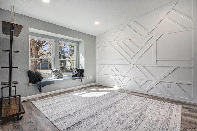 interior space with recessed lighting, baseboards, wood finished floors, and a decorative wall