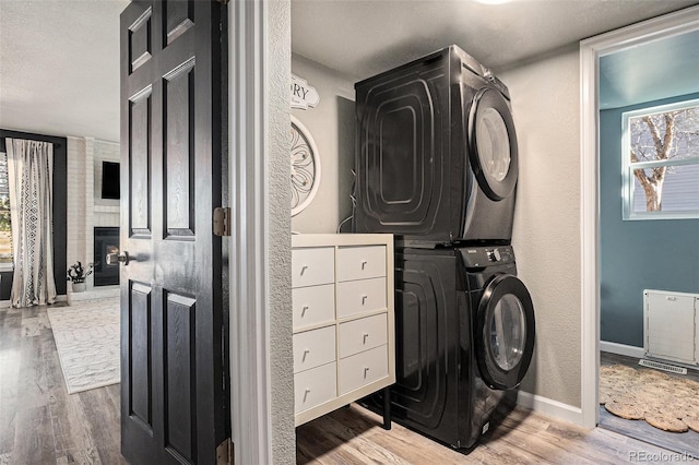 washroom featuring laundry area, wood finished floors, baseboards, and stacked washing maching and dryer