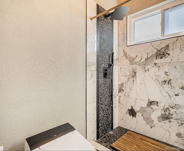 full bath featuring a tile shower and a textured wall