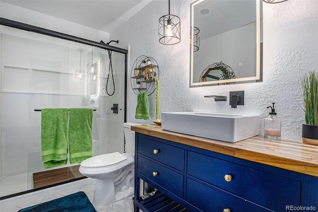 bathroom featuring vanity, toilet, a shower stall, and a textured wall