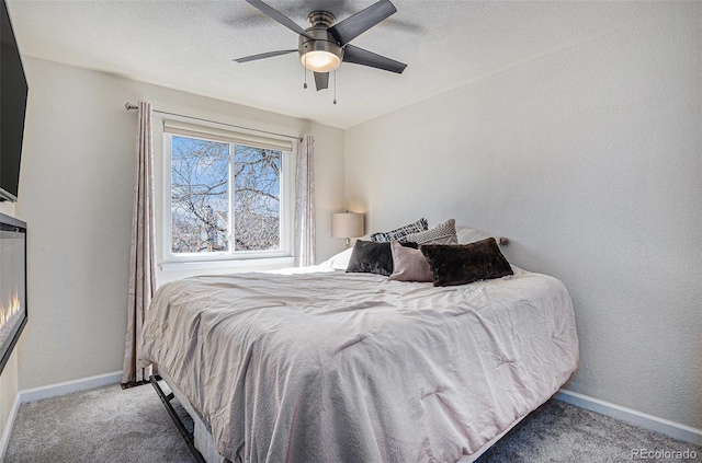 bedroom with carpet, baseboards, a textured wall, and ceiling fan