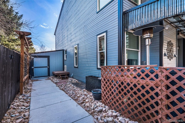 view of side of home featuring an outbuilding, a storage unit, and a fenced backyard