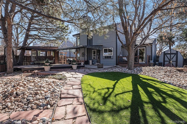 rear view of house featuring fence, a shed, a lawn, an outdoor structure, and a deck