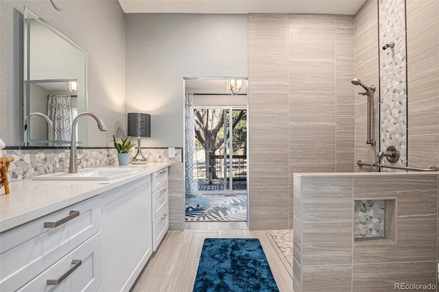 full bath featuring wood finish floors, tile walls, vanity, and a tile shower