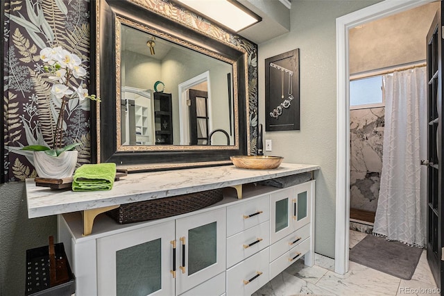 bathroom with curtained shower, vanity, a textured wall, and marble finish floor