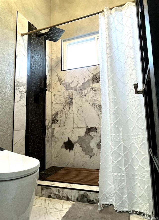 bathroom with a shower stall, toilet, a textured wall, and marble finish floor