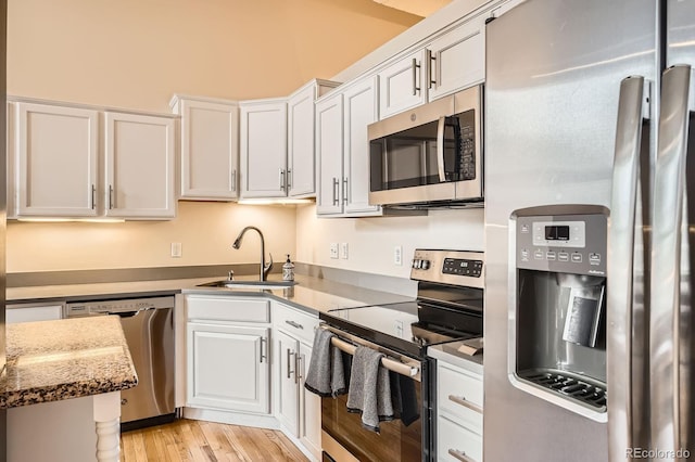 1555 California St Unit 304, Denver, CO 80202 - kitchen featuring stainless steel appliances, a sink, white cabinetry, light wood-style flooring, and light stone countertops