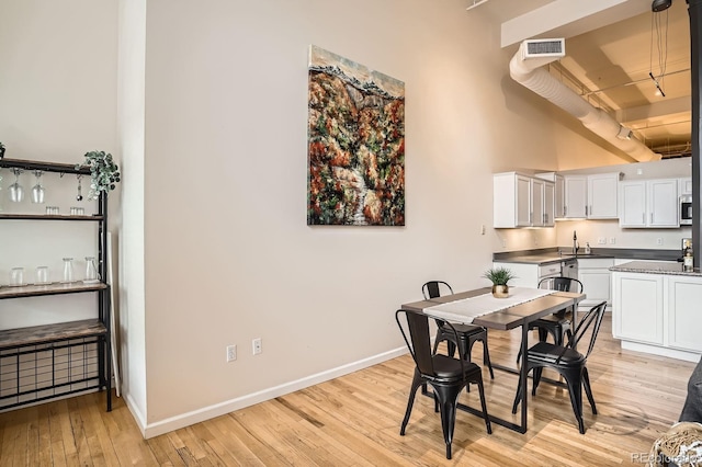 1555 California St Unit 304, Denver, CO 80202 - dining space featuring light wood-style flooring, baseboards, and a towering ceiling