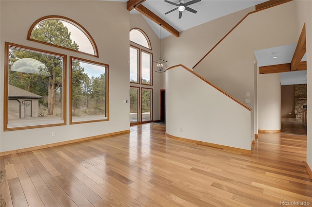 unfurnished living room with plenty of natural light, beam ceiling, and light wood-style floors