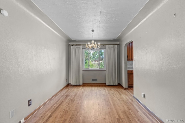 4815 S Pennsylvania St, Englewood, CO 80113 - unfurnished dining area with a chandelier, arched walkways, light wood-style flooring, and a textured ceiling