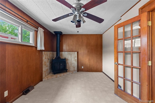 4815 S Pennsylvania St, Englewood, CO 80113 - unfurnished living room with a wood stove, light flooring, wooden walls, and ceiling fan