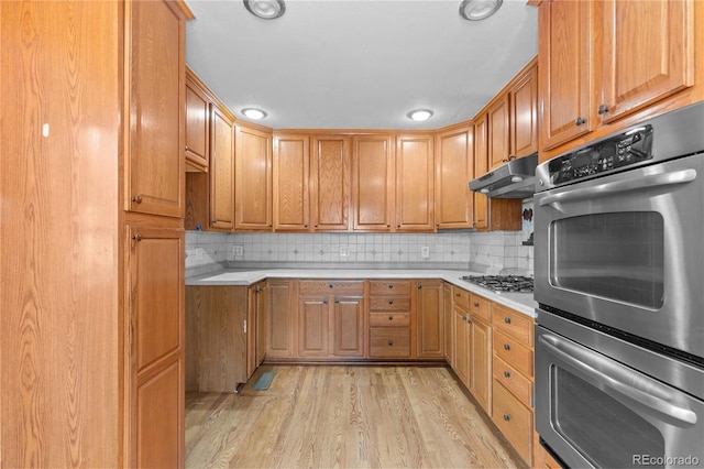4815 S Pennsylvania St, Englewood, CO 80113 - kitchen with light countertops, under cabinet range hood, appliances with stainless steel finishes, light wood-style floors, and tasteful backsplash