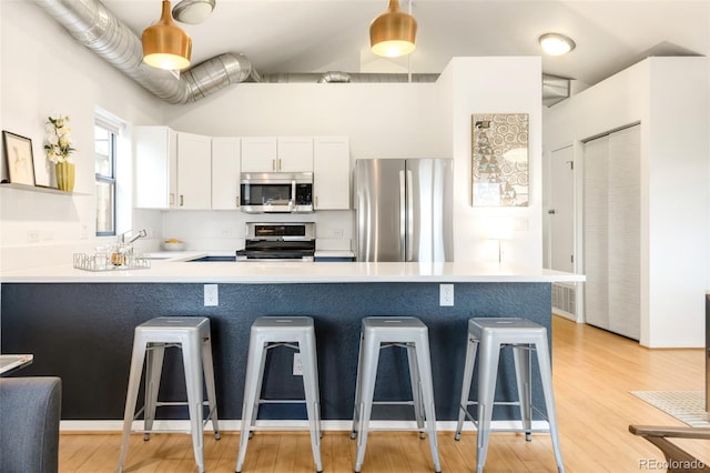 3069 Tejon St Unit B, Denver, CO 80211 - kitchen with stainless steel appliances, a breakfast bar, a peninsula, light countertops, and white cabinetry