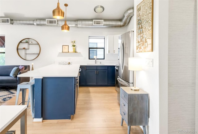 3069 Tejon St Unit B, Denver, CO 80211 - kitchen featuring blue cabinetry, light wood finished floors, plenty of natural light, and a peninsula