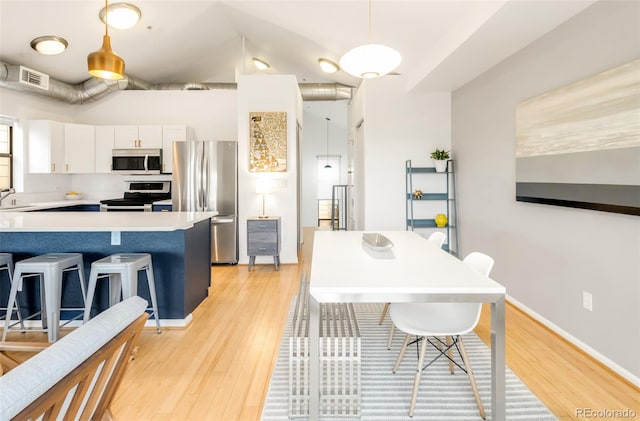 3069 Tejon St Unit B, Denver, CO 80211 - kitchen with appliances with stainless steel finishes, light wood-style flooring, white cabinets, light countertops, and a kitchen breakfast bar