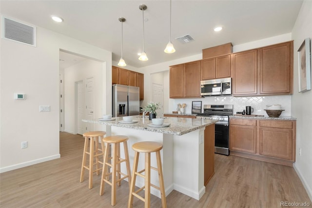 kitchen with appliances with stainless steel finishes, visible vents, backsplash, and a kitchen breakfast bar