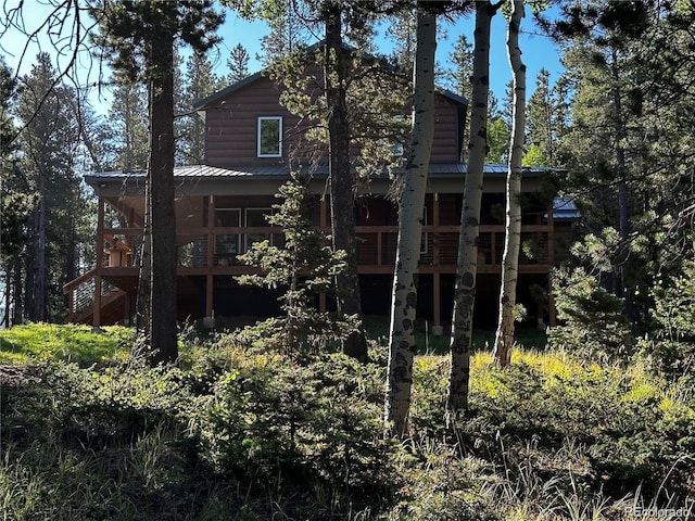 rear view of property with log veneer siding, metal roof, and a wooden deck