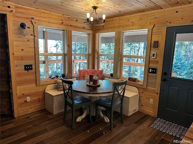 dining room featuring dark wood-style floors, wood walls, wooden ceiling, and an inviting chandelier