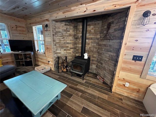 living room featuring wood finish floors, a wealth of natural light, wood walls, and a wood stove