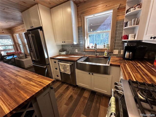 kitchen with wooden counters, dark wood-type flooring, white cabinets, stainless steel appliances, and a sink