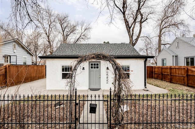 bungalow-style home with a gate, a fenced front yard, and stucco siding