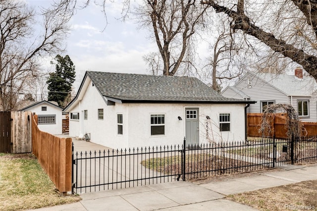 view of front of house with a fenced front yard, stucco siding, and a shingled roof