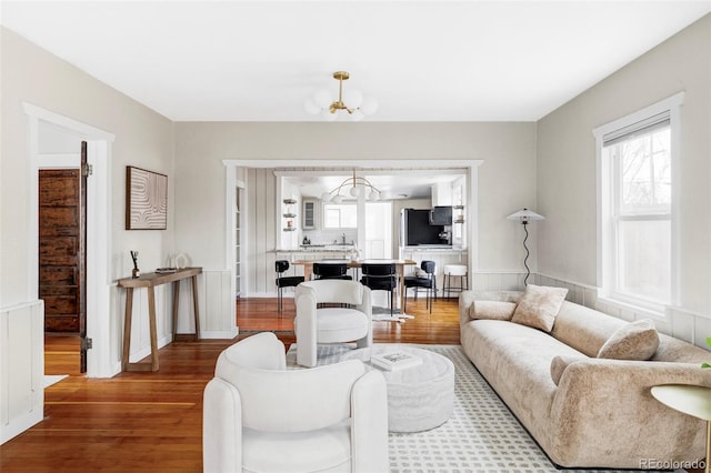 living room featuring a wainscoted wall, wood finished floors, and a chandelier