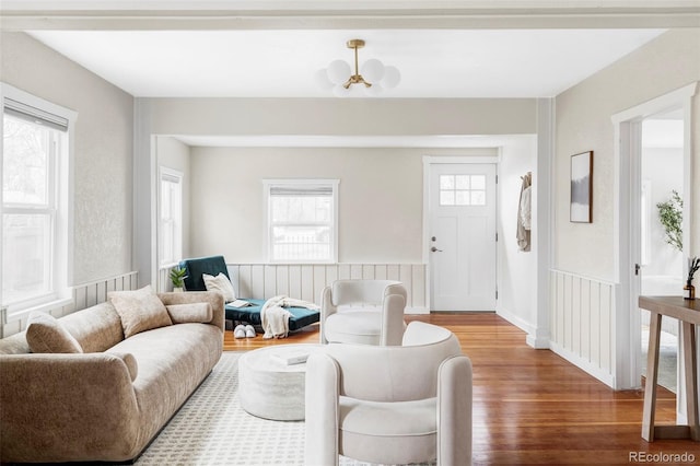 living area featuring a wainscoted wall, an inviting chandelier, and wood finished floors