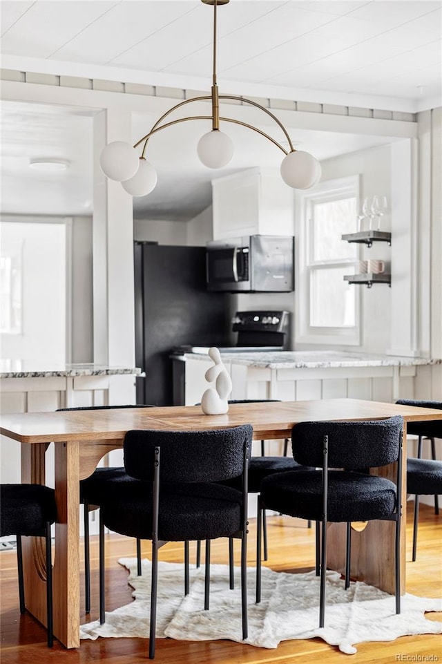 kitchen featuring stainless steel microwave, wood finished floors, and freestanding refrigerator