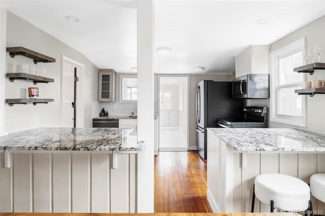 kitchen with open shelves, appliances with stainless steel finishes, a peninsula, and a healthy amount of sunlight