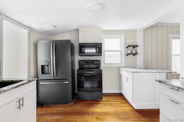 kitchen featuring black appliances, white cabinets, light wood-style floors, and a wealth of natural light