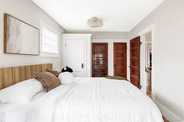 bedroom featuring baseboards and two closets