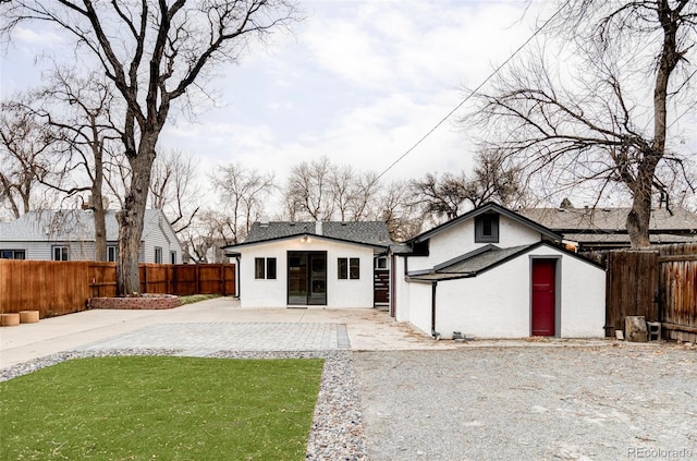 view of front of house featuring an outbuilding, a patio, a front lawn, and a fenced backyard