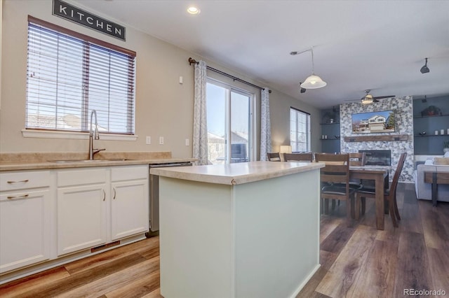 kitchen with decorative light fixtures, sink, hardwood / wood-style flooring, and white cabinetry