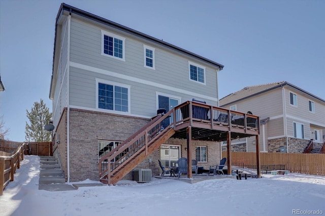 snow covered back of property featuring cooling unit and a deck