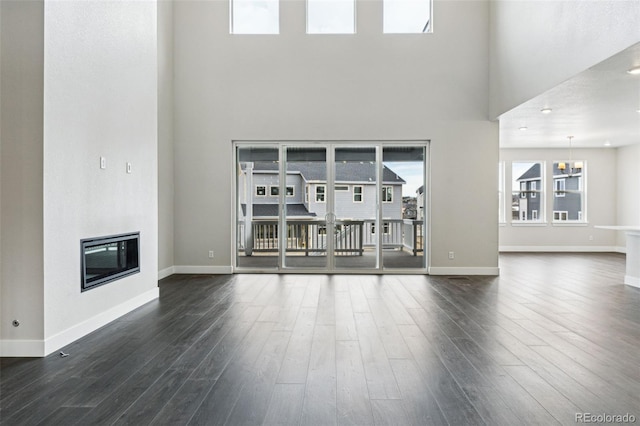 unfurnished living room with heating unit, a chandelier, a high ceiling, and dark hardwood / wood-style floors