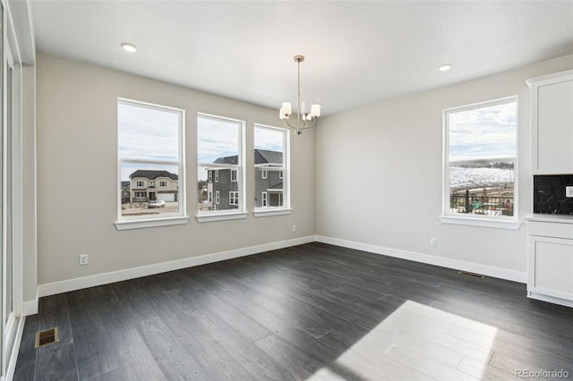 unfurnished dining area with a chandelier and dark hardwood / wood-style flooring