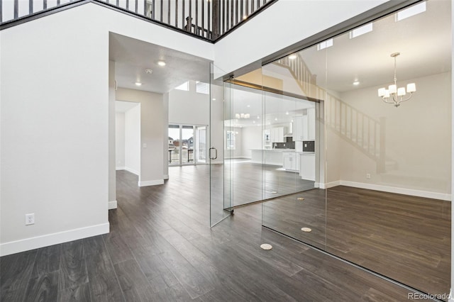 unfurnished living room with a towering ceiling, dark wood-type flooring, and a notable chandelier