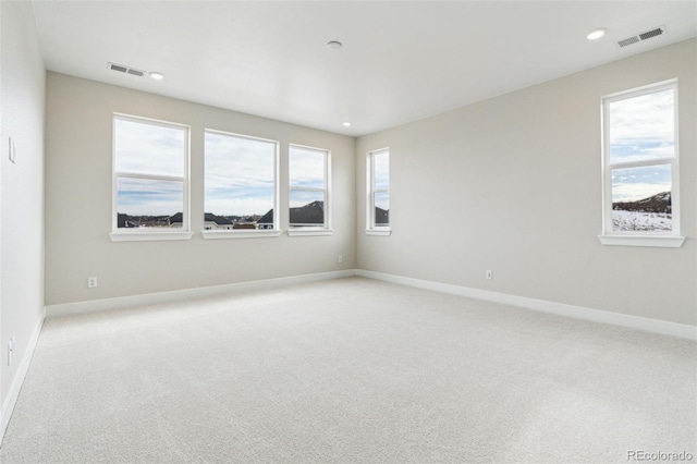 spare room featuring light carpet and a wealth of natural light