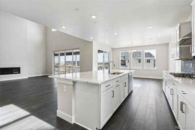 kitchen with a center island with sink, sink, decorative light fixtures, stainless steel appliances, and white cabinets