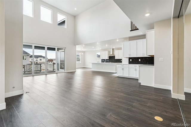 unfurnished living room featuring plenty of natural light, dark hardwood / wood-style floors, and a towering ceiling